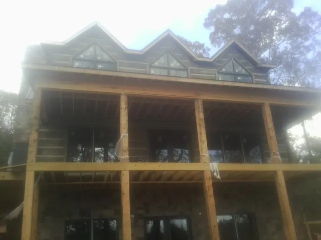 Dormers and porch framing on a large log home under construction — Roof Coating work by our crew in Walton