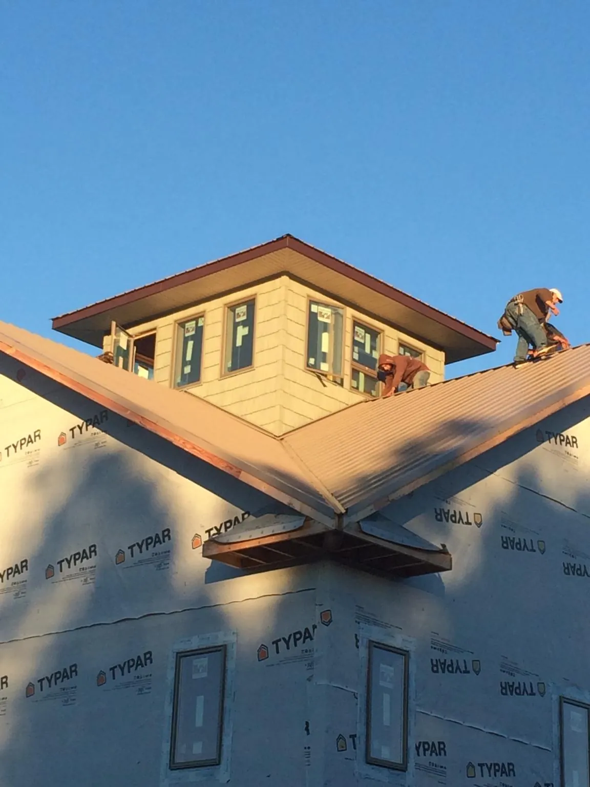 Roofers working around a rooftop cupola on a new metal roof at sunset — Roof Waterproofing in Walton by Roofing Brothers